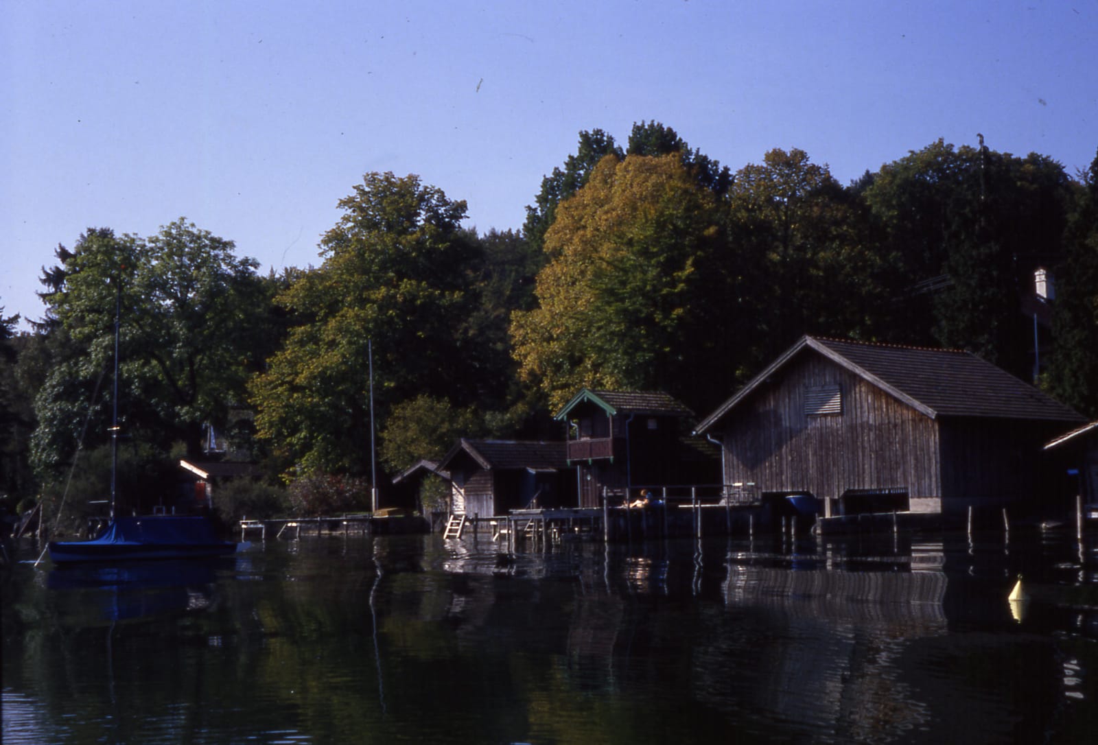 Bootshäuser am Seeufer, im Wasser gespiegelt (Dia-Scan)