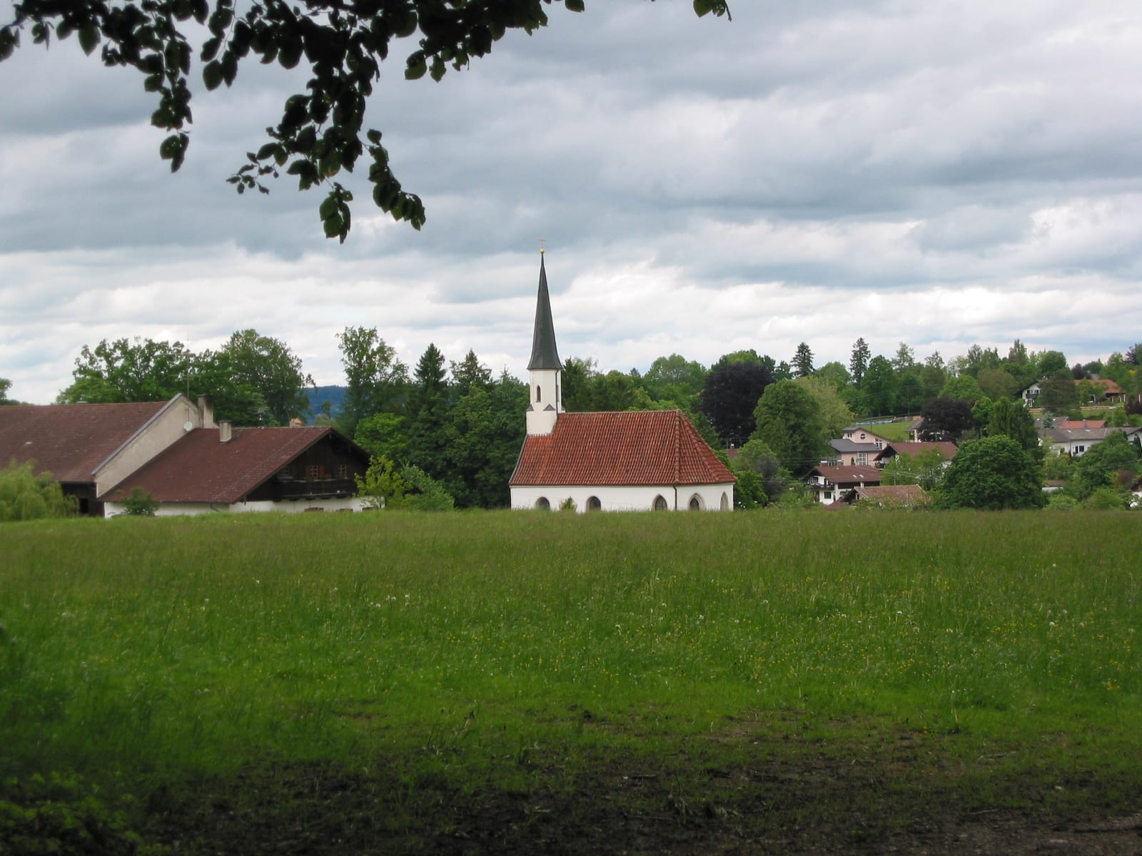 Dorfkirche über weiter Wiese unter Wolkenhimmel