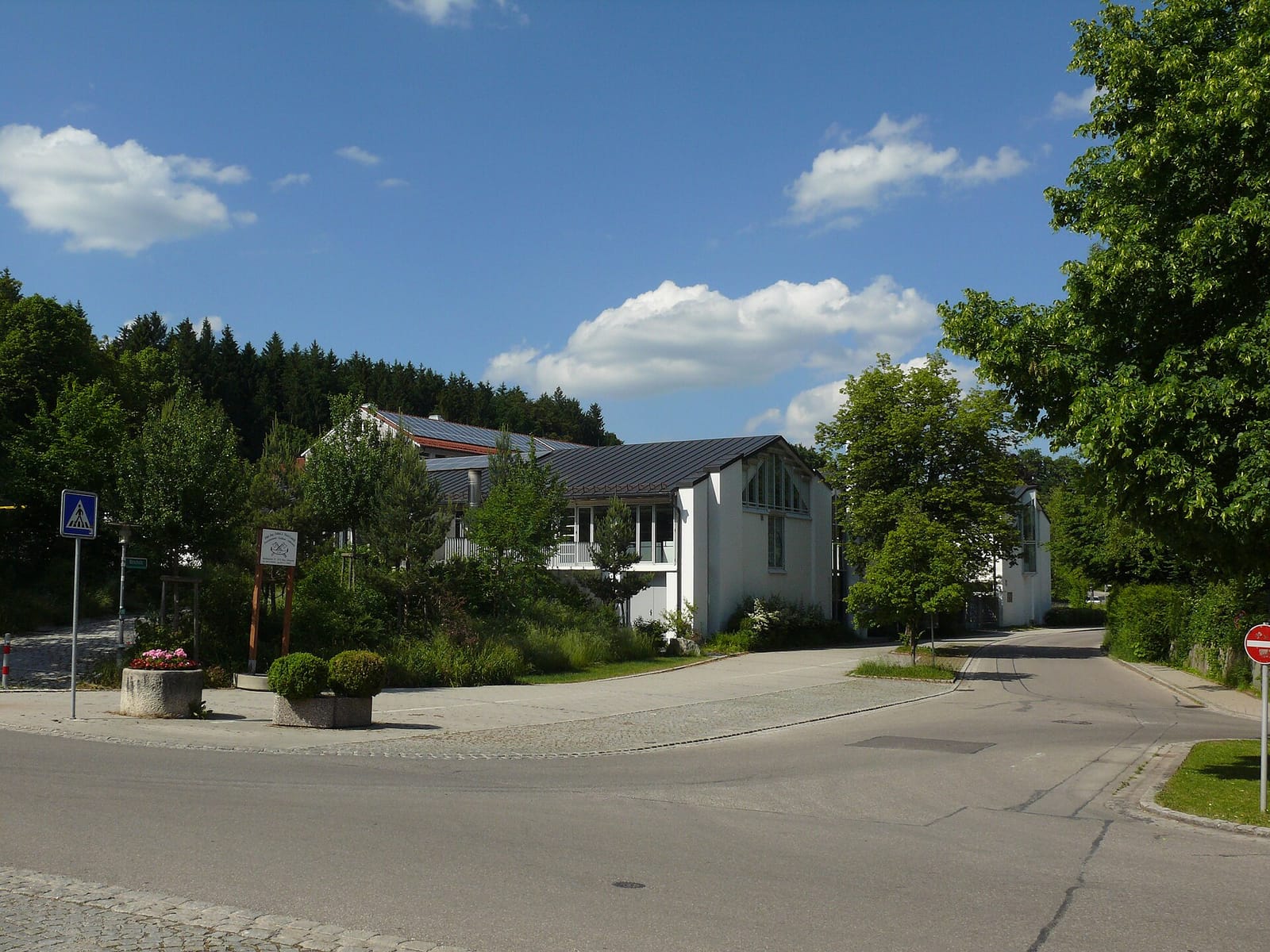 Rainer-Maria-Rilke-Gymnasium in Icking. An einer Fassade sind zwei Reliefs angebracht, an einer anderen eine große Sonnenuhr mit Reliefmedaillons der zwölf Tierkreiszeichen. Der Di